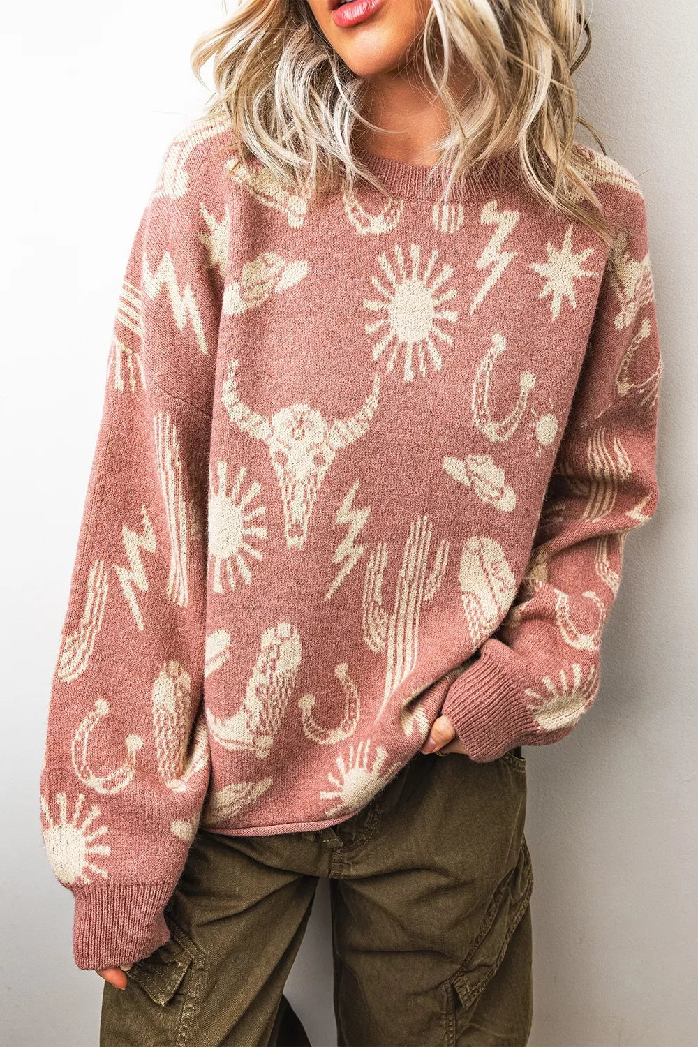 On-model front view of a dusty rose sweater with cream western motifs including cacti and suns
