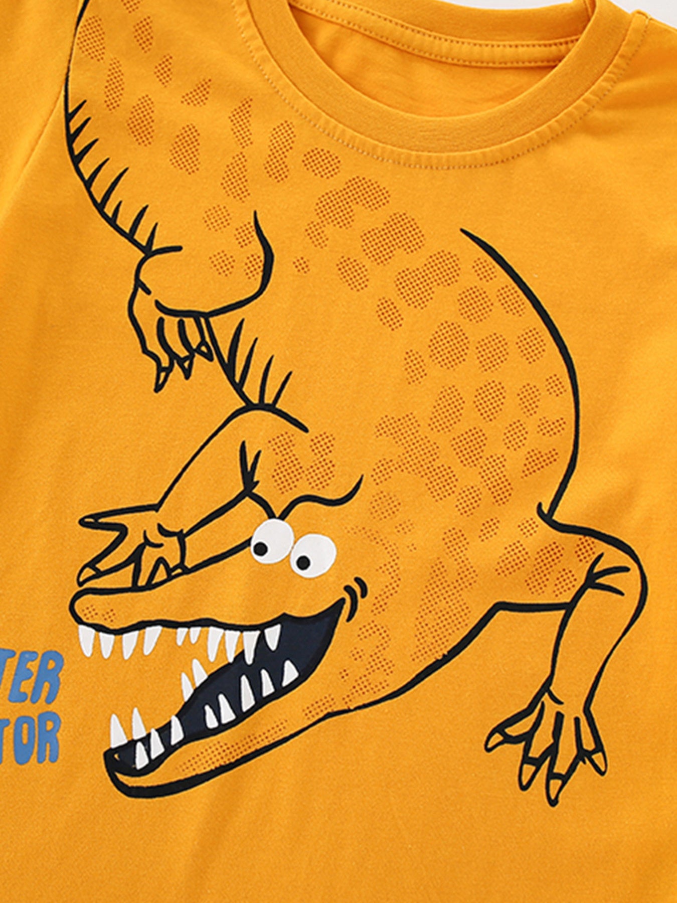 Close-up detail of the cartoon alligator head with open jaws on tangerine fabric