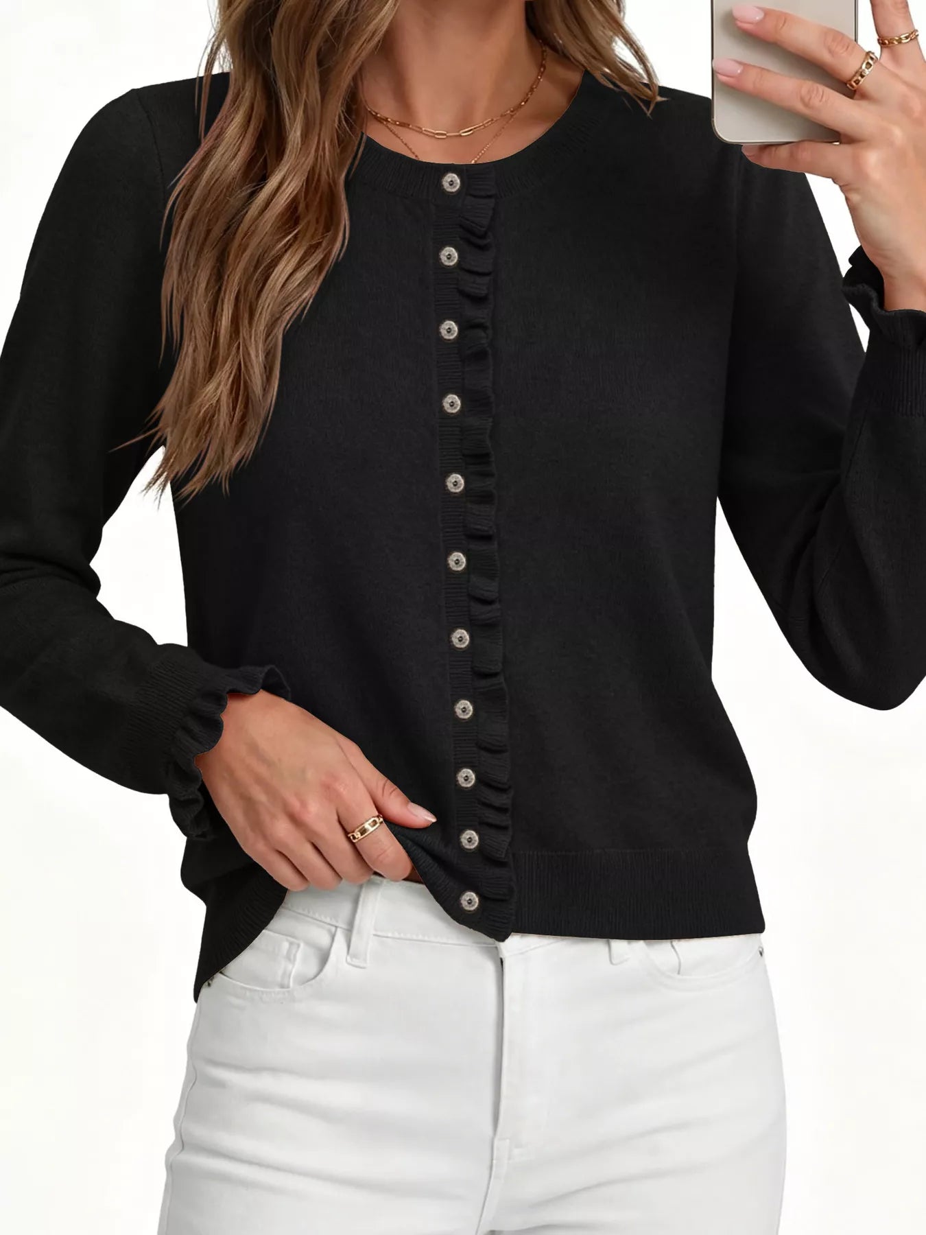 Close front view of black ruffle trimmed button down cardigan with white jeans on white background