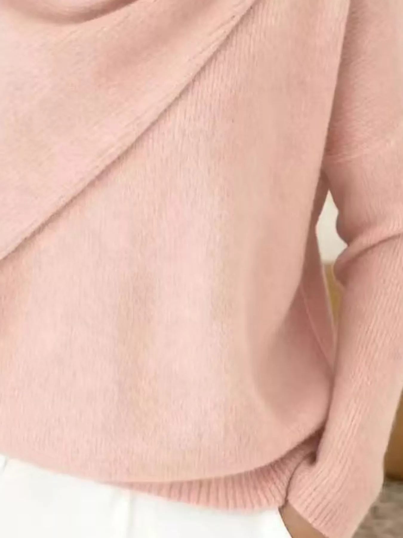 Close-up of the pale pink sweater lower body and long sleeve showing the ribbed hem and knit texture