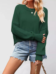 Front view of a dark green crew neck dropped shoulder sweater with ribbed cuffs worn with denim shorts.