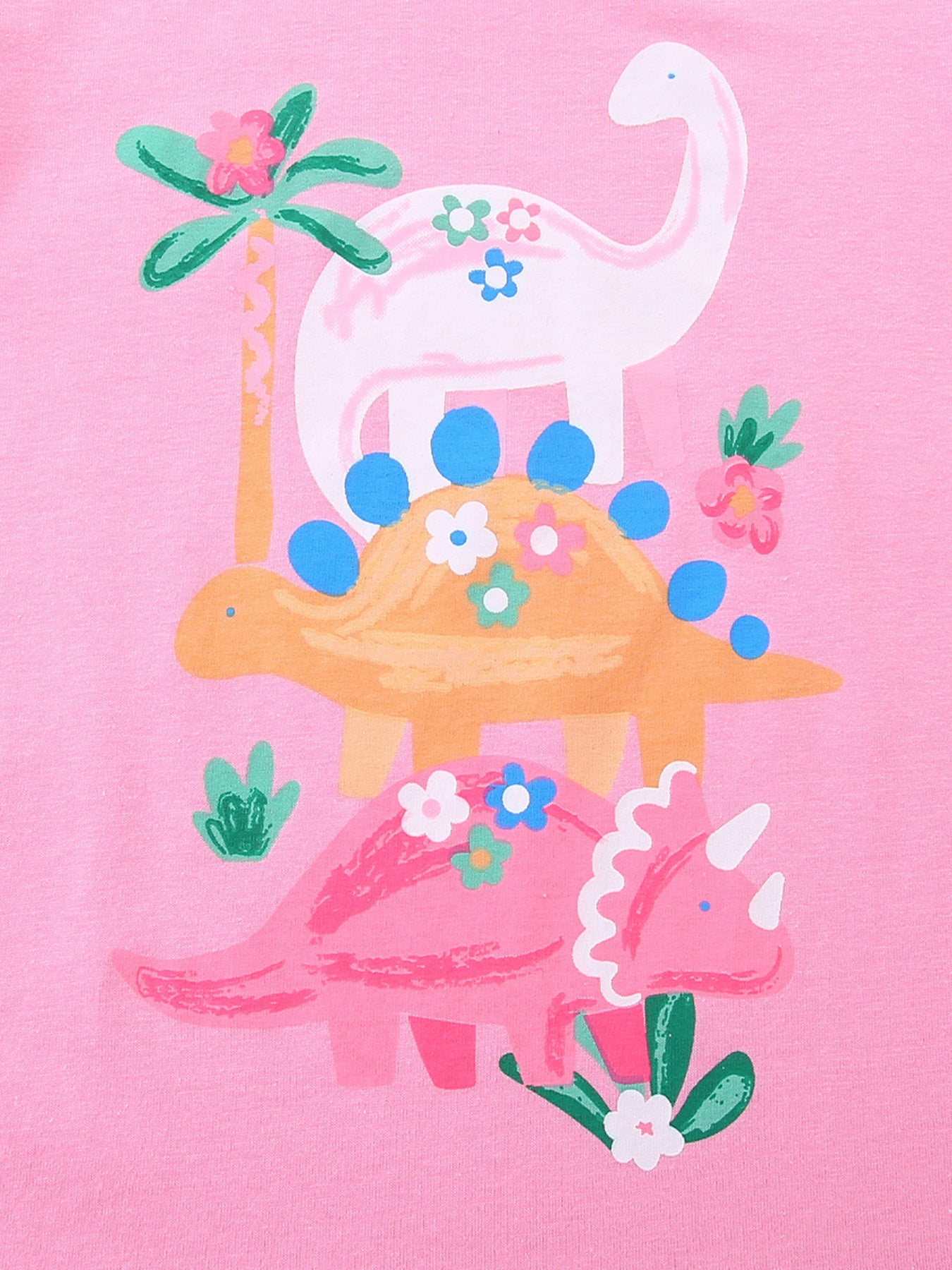 Close up of pink children's t-shirt print with three dinosaurs flowers and palm trees