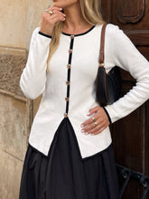 Front view of white long sleeve knit top with black trim and gold buttons down the front.