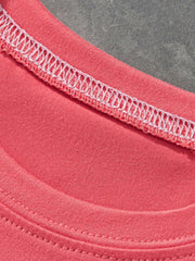 Close-up of coral children's t-shirt neckline showing white stitching and soft fabric texture
