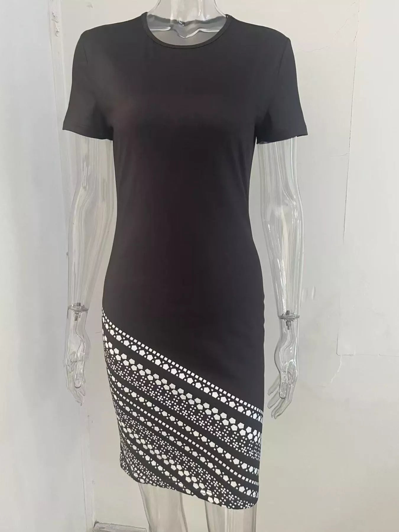 Black round neck bodycon mini dress with white geometric diagonal skirt panel, front view on mannequin
