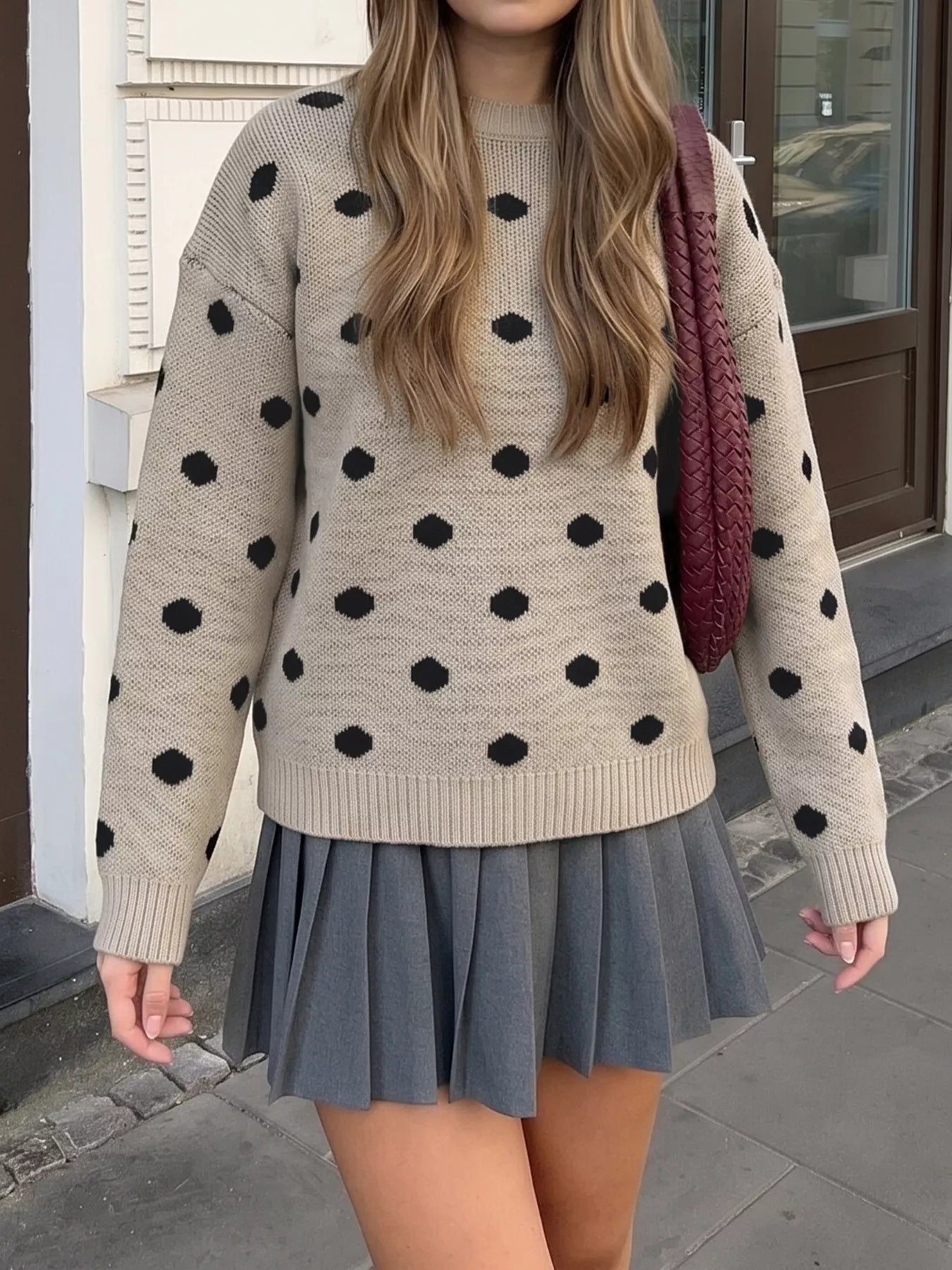 Khaki polka dot dropped shoulder sweater worn with grey pleated skirt outdoors