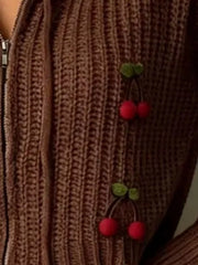 Close up of brown knit zip up sweater showing ribbed texture and red cherry appliques