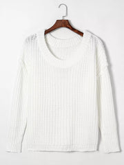 White ribbed knit sweater with round neckline and long sleeves hanging on a wooden hanger.