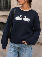 Front view of a navy sweater with two facing white swans and white neck trim