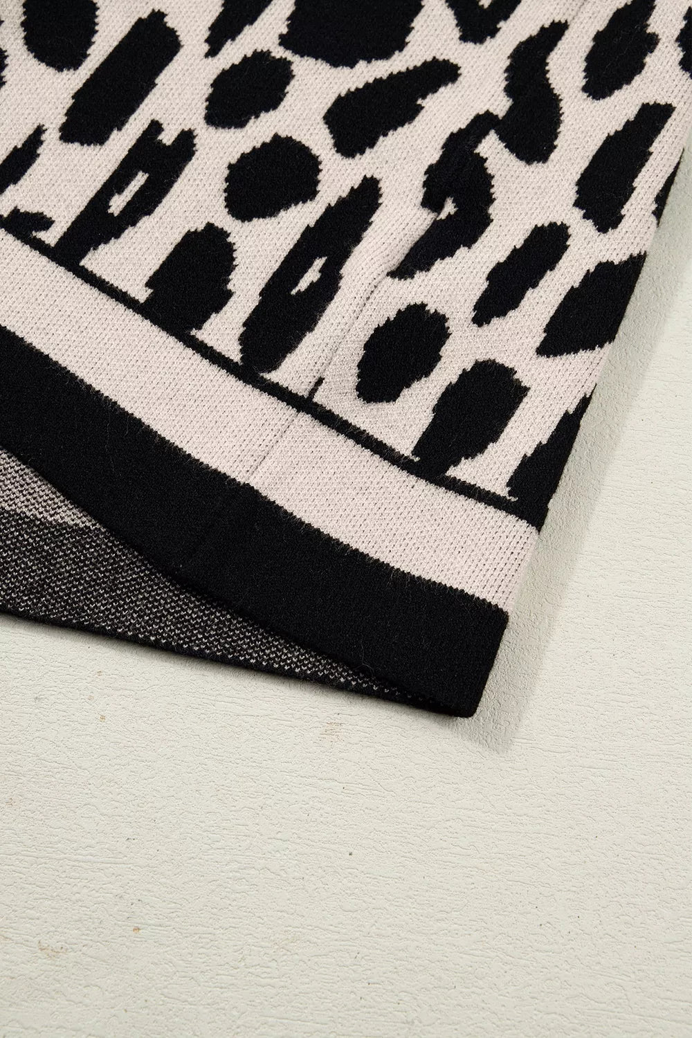 Close up detail of the striped black and cream hem on the leopard print knit sweater.