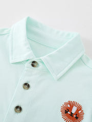 Close-up of the mint blue polo collar, button placket and embroidered lion motif