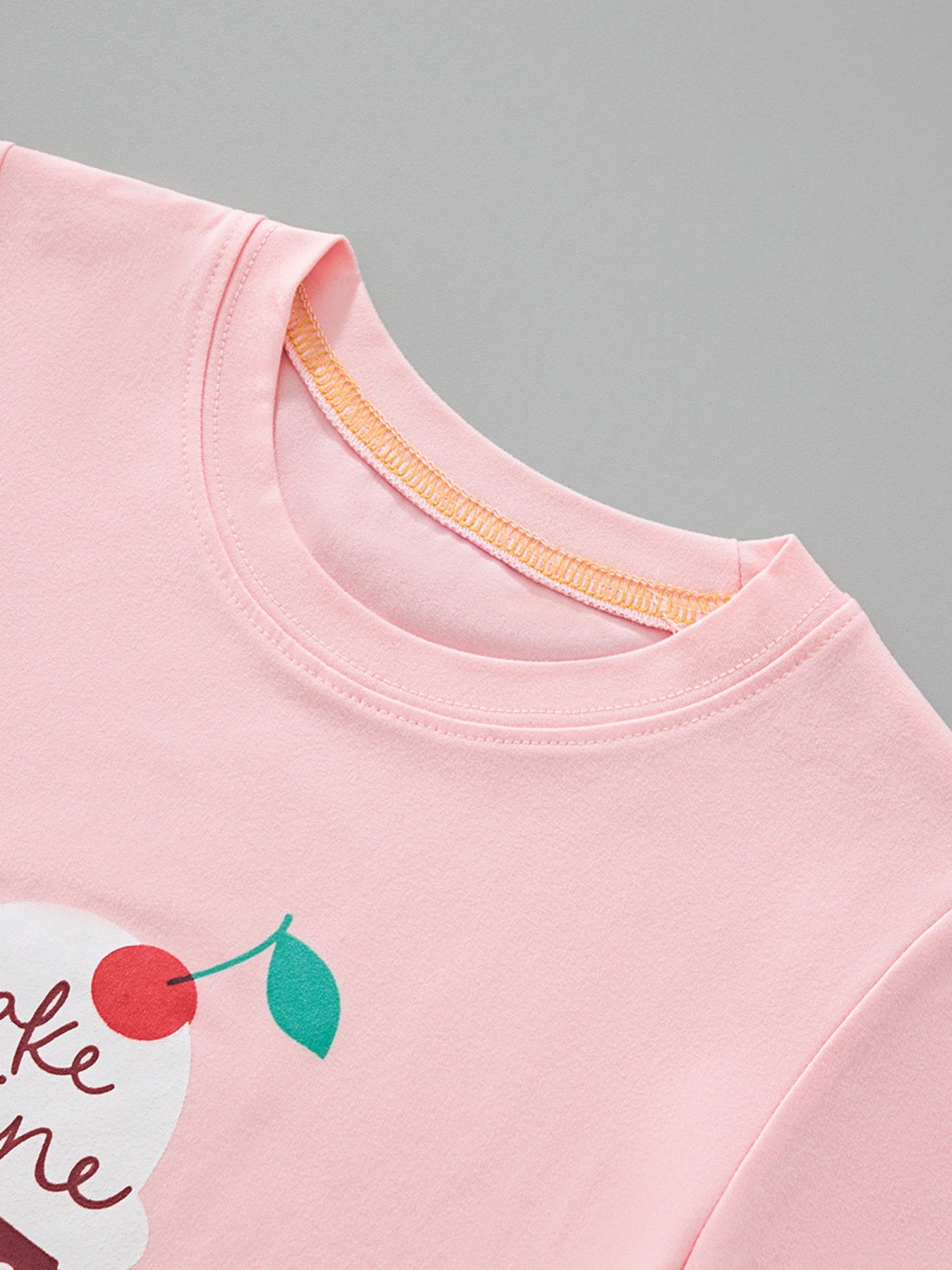 Close-up of the blush pink children's t-shirt neckline and the cherry on the ice cream graphic