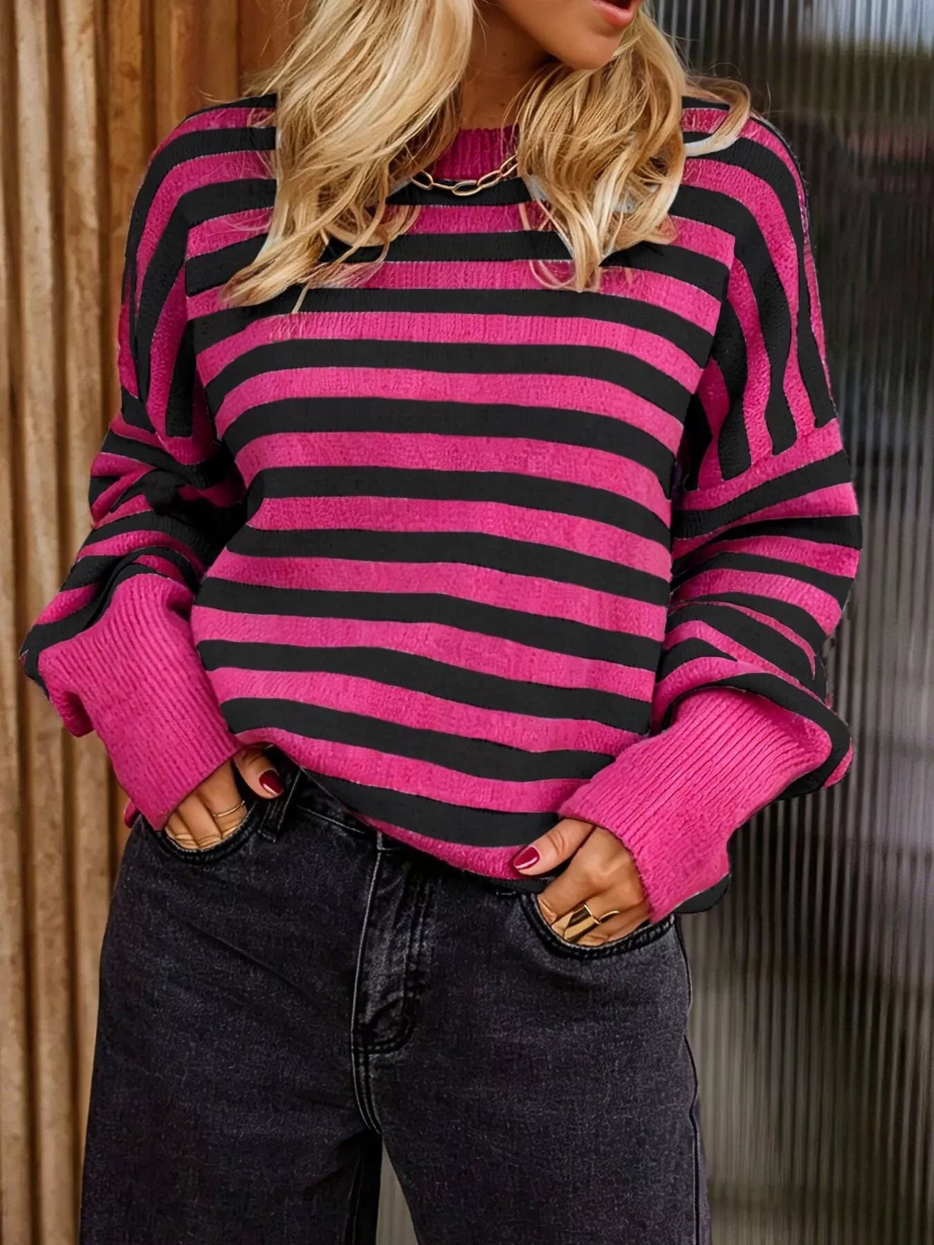 On-model front view of a rose red and black striped crew neck sweater
