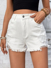 Women's high-rise distressed denim shorts with buttons, raw hems, and pockets.