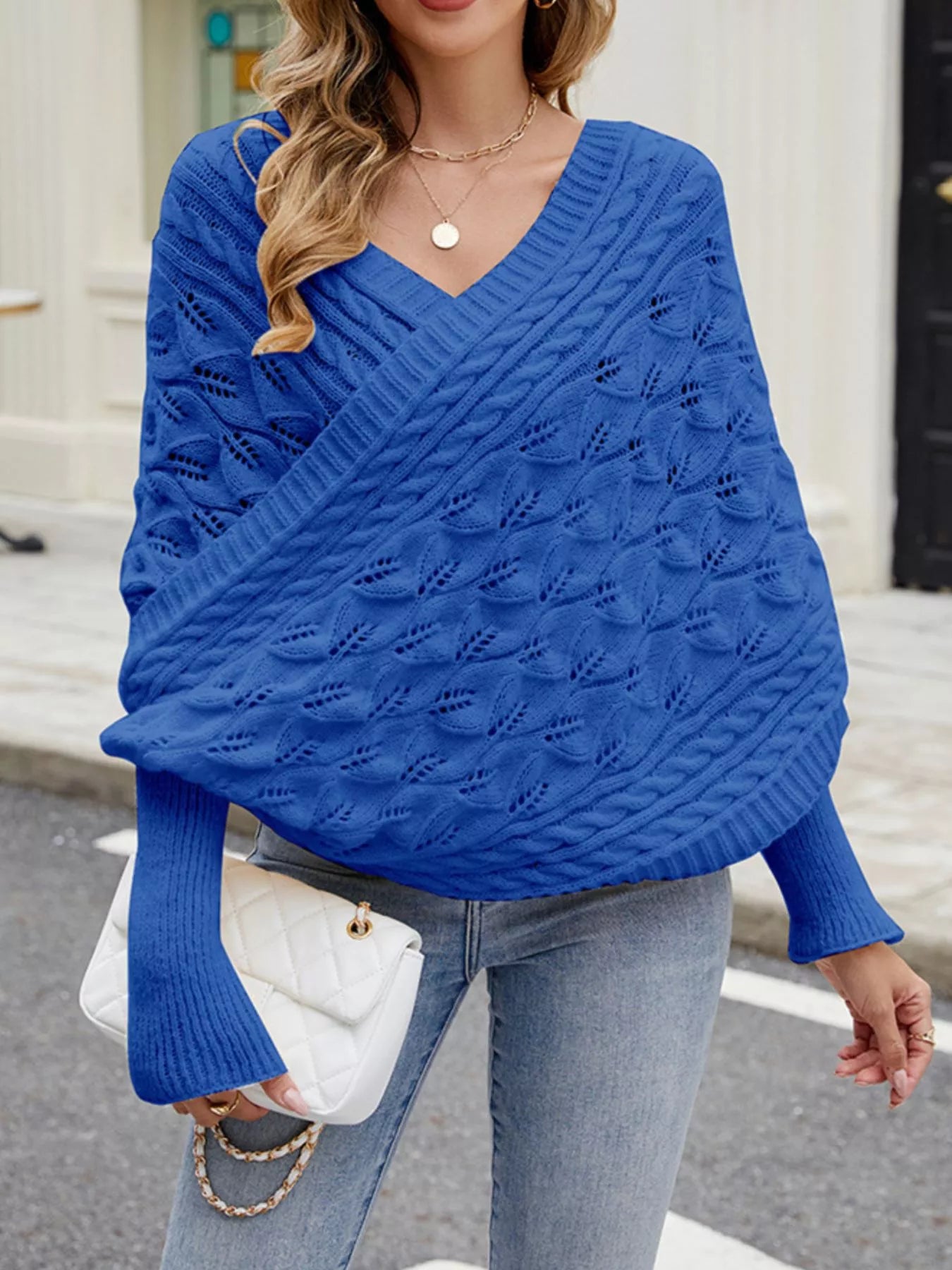 Front view of blue cable knit batwing sweater with V neckline and leaf pattern.