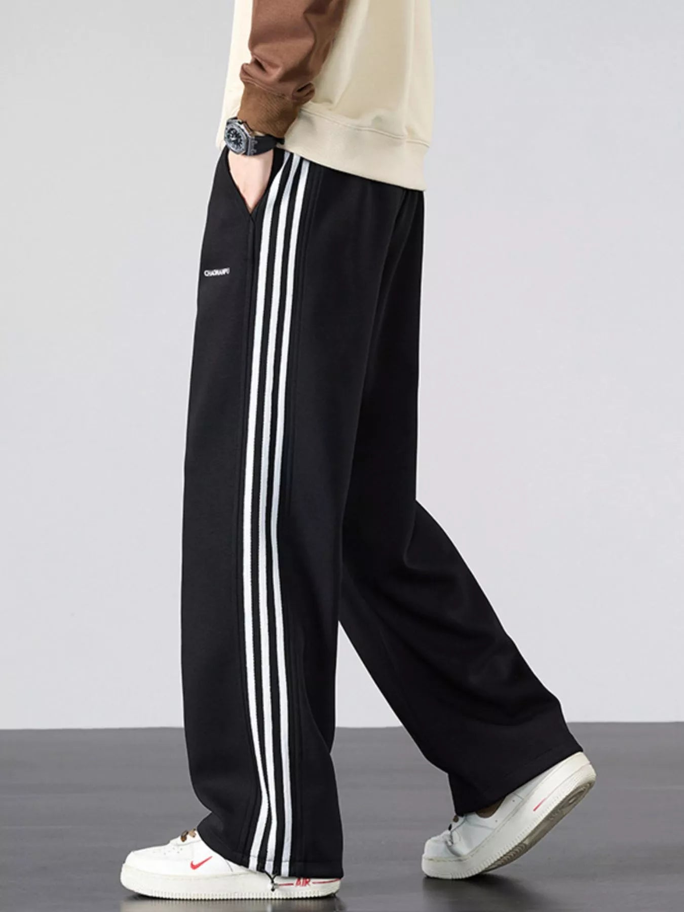 Men's black striped wide-leg sweatpants with a drawstring waist and pockets.