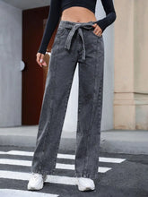 Women's dark gray straight-leg jeans with tie details and pockets.