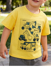 Yellow children's short sleeve t-shirt with excavators, a steamroller, and a crane truck, shown worn outdoors