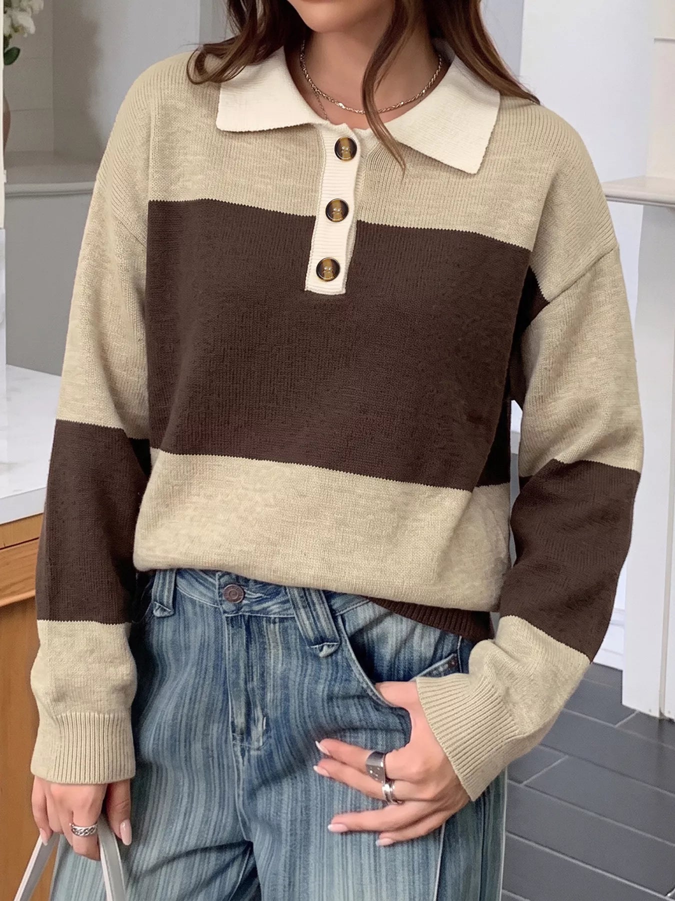 Front view of beige and brown polo sweater with long sleeves and ribbed cuffs.