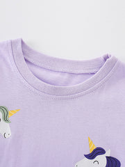 Close view of the round neckline with unicorn heads at the edges of the light purple T-shirt