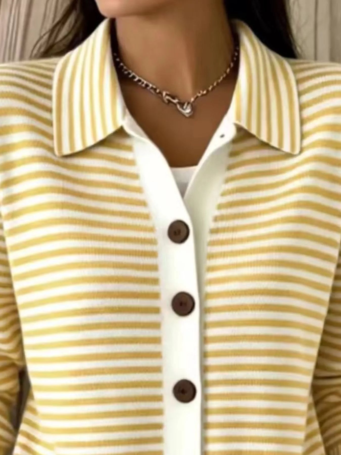 Close-up of the collar and brown buttons on a yellow and white striped knit cardigan