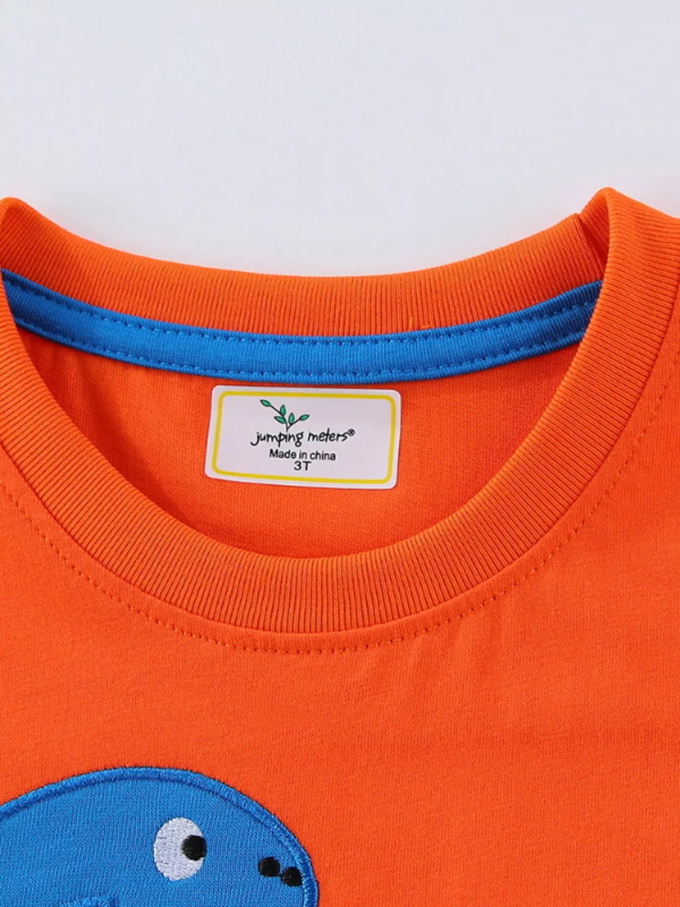 Close view of the orange children's tee neckline with a blue inner trim and neat stitching