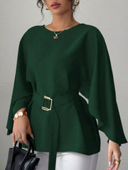 Dark green round neck blouse front view holding black handbag with gold buckle belt
