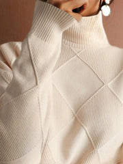 Close up of the cream ribbed turtleneck and diamond patterned shoulder