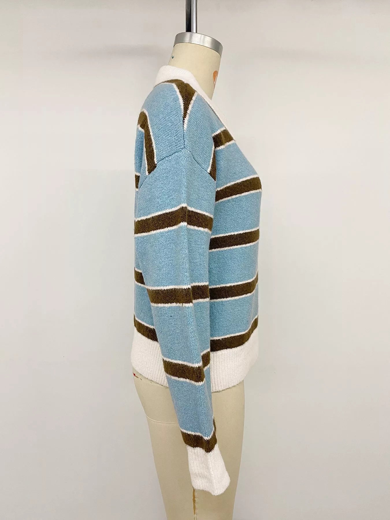 Side view of striped blue polo sweater on a mannequin, showing long sleeves and ribbed hem.
