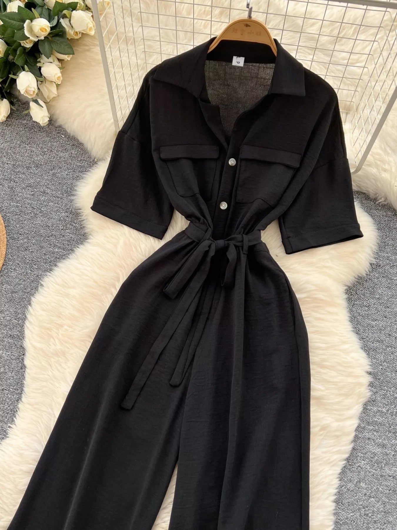Women's wide-leg jumpsuit with buttons, a tied belt, and pockets.
