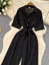 Women's wide-leg jumpsuit with buttons, a tied belt, and pockets.