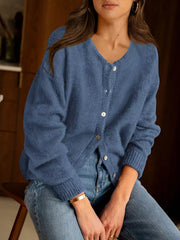 Seated front view of haze blue button down cardigan with white buttons and blue jeans