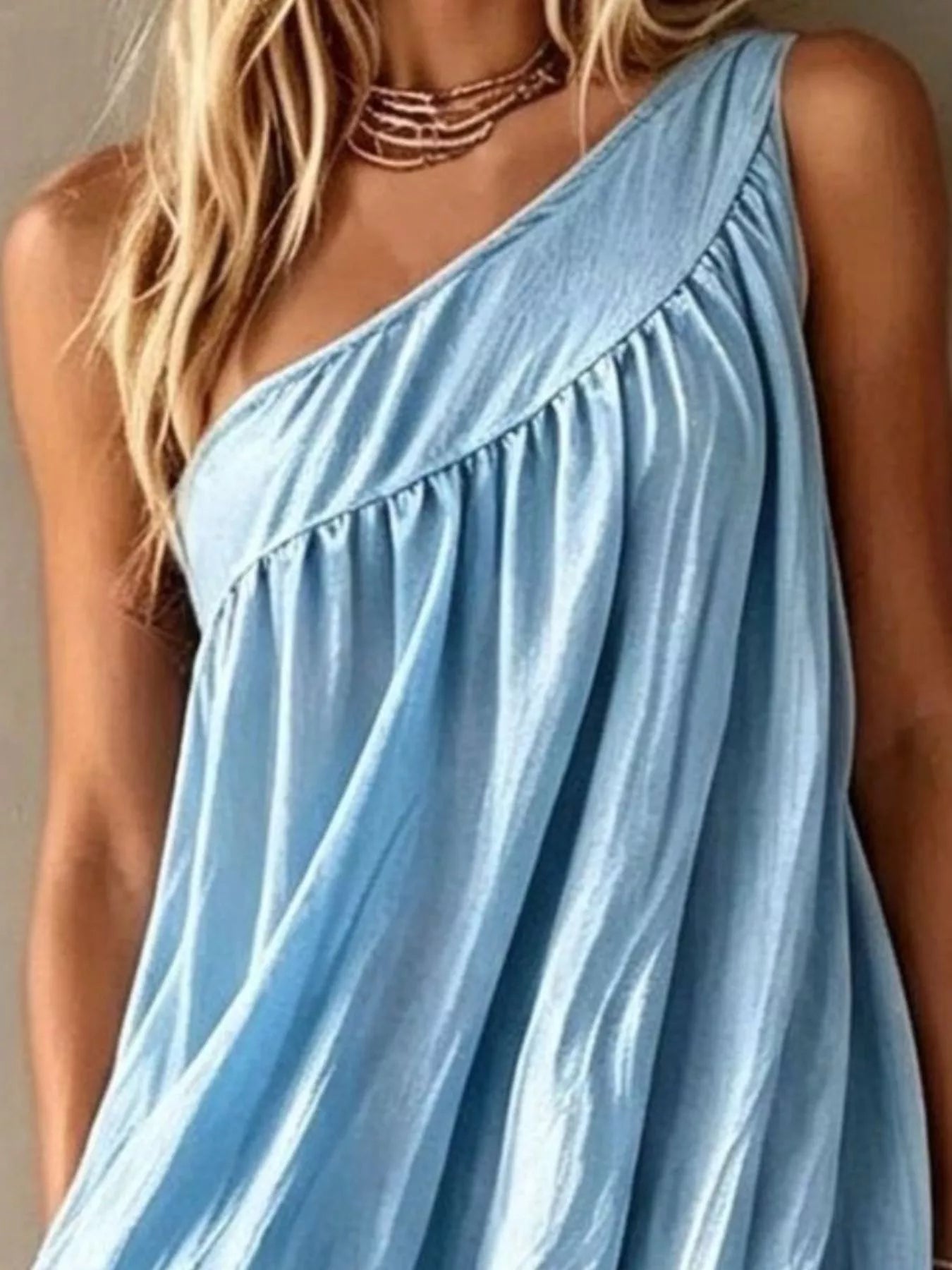 Close view of a light blue one shoulder maxi dress showing the diagonal neckline and gathers