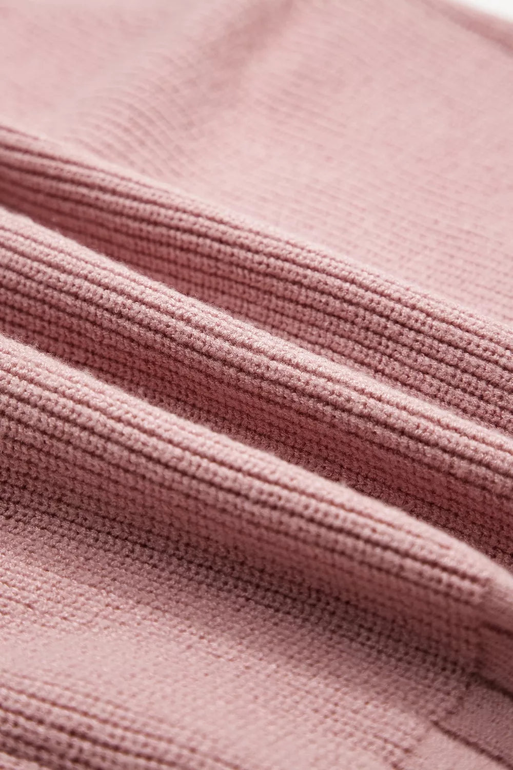 Close-up of the ribbed knit fabric texture on a dusty pink cardigan