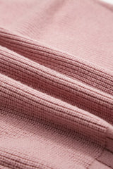 Close-up of the ribbed knit fabric texture on a dusty pink cardigan