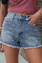 Women's washed denim shorts with pearl beading and raw hems.