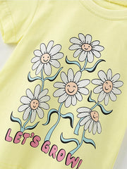 Angled close view of the smiling daisy print with wavy stems on the light yellow children's tee