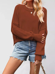 Front view of a rust brown crew neck dropped shoulder sweater with ribbed cuffs worn with denim shorts.