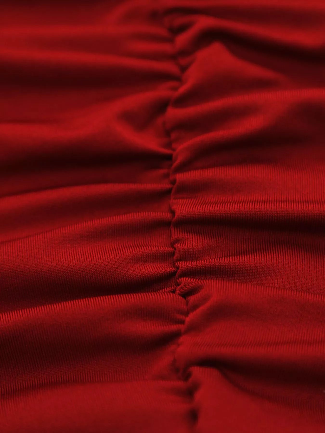 Close detail of burgundy ruched fabric and side seam of bodycon mini dress