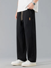 Men's black loose-fit casual pants with a drawstring waist and pockets.