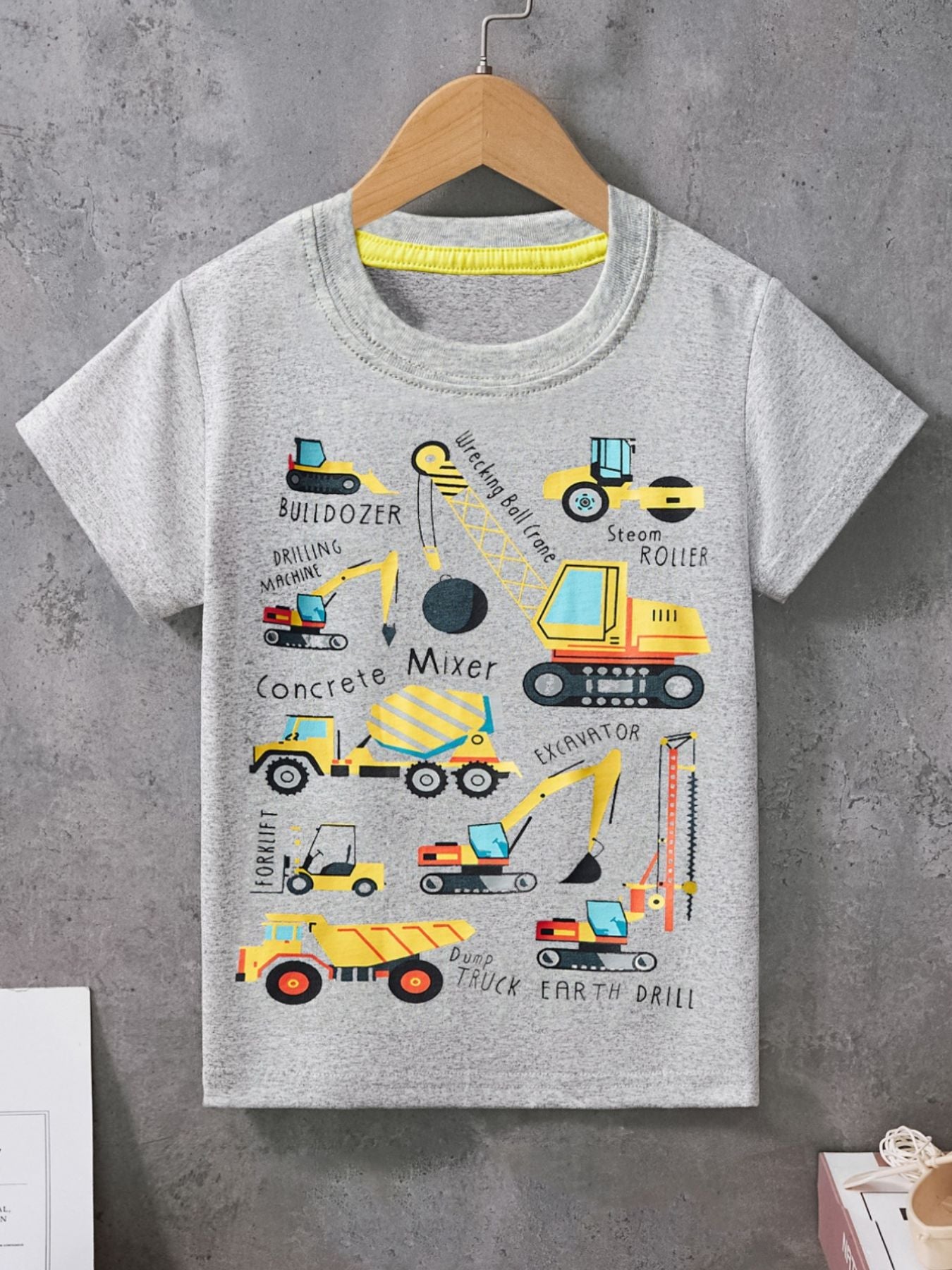 Light gray children's crew neck short sleeve T-shirt with construction vehicle graphics, hanging on a hanger in front view