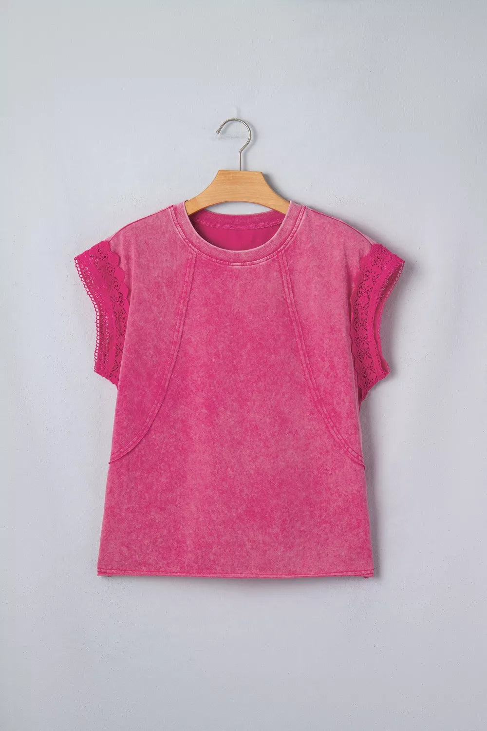 Pink mineral-wash top with raw seam details and lace-trimmed cap sleeves on a hanger