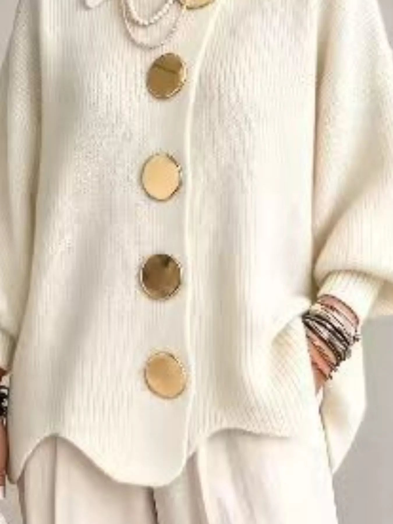 Close up of the cream cardigan lower gold buttons and scalloped hem