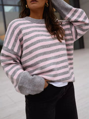 On-model front view of a gray and pink striped crew neck sweater, arm raised