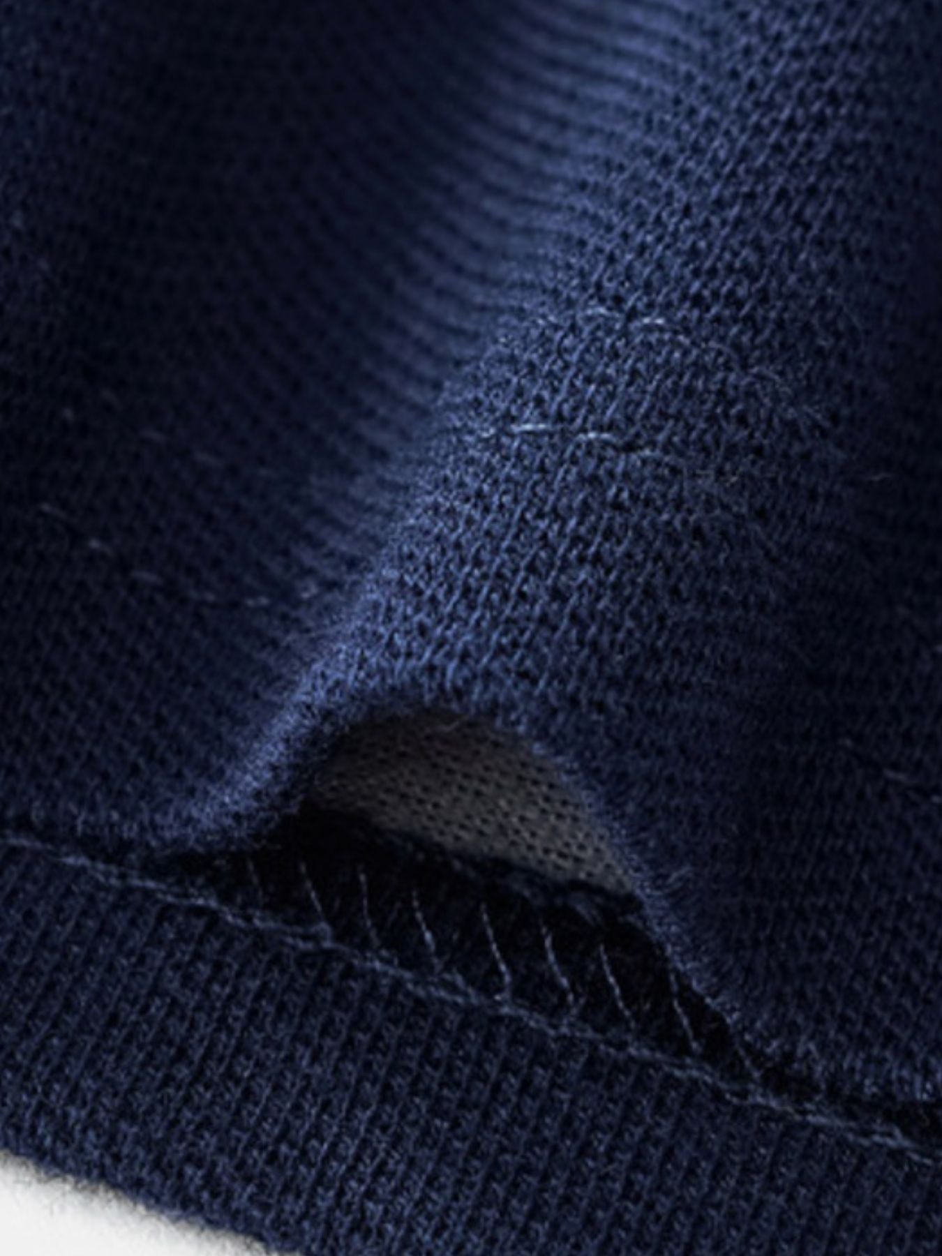 Close-up of the dark navy piqué fabric texture and stitching at the hem