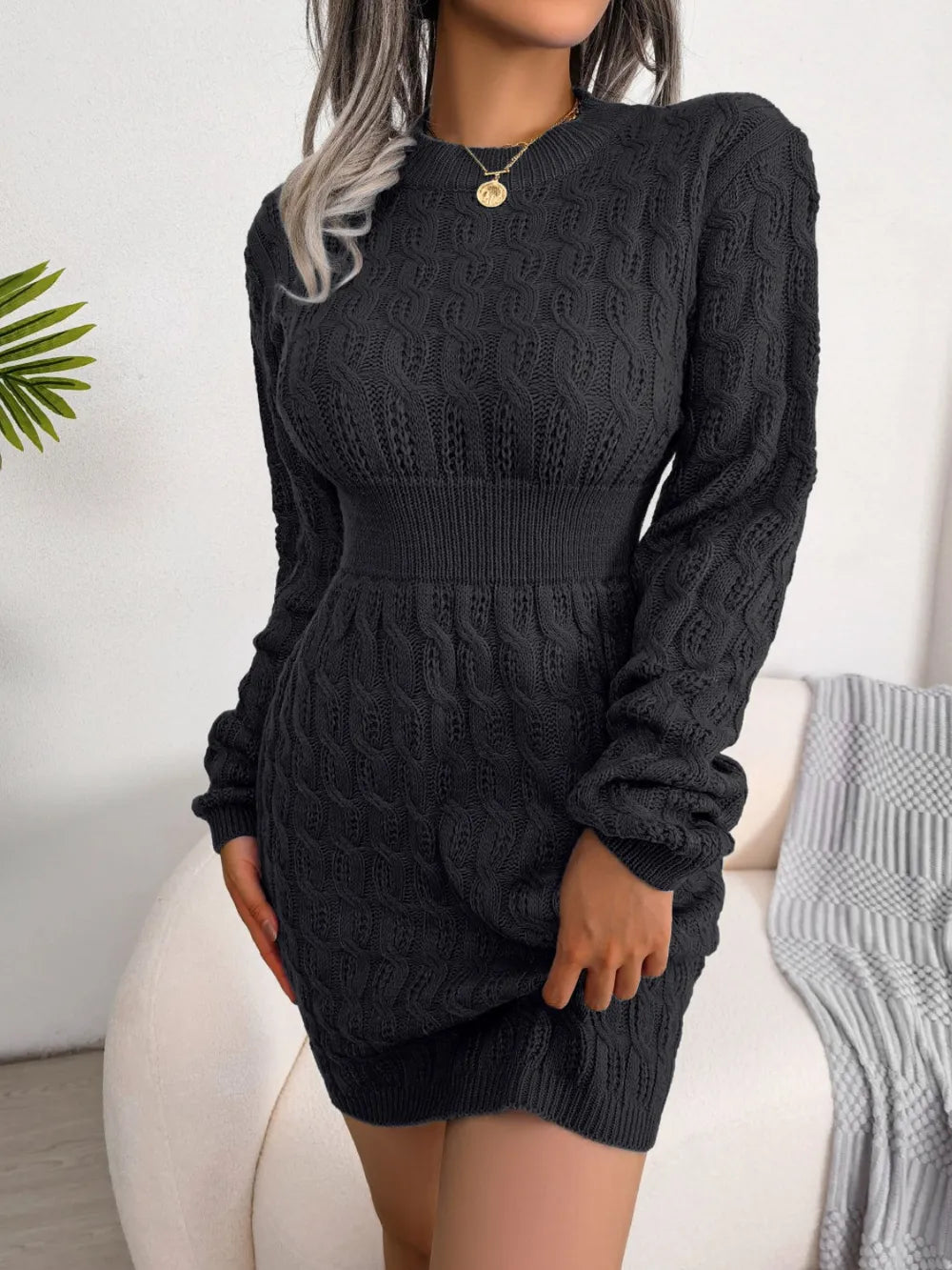 Women's black cable-knit mini wrap sweater dress with a round neckline.