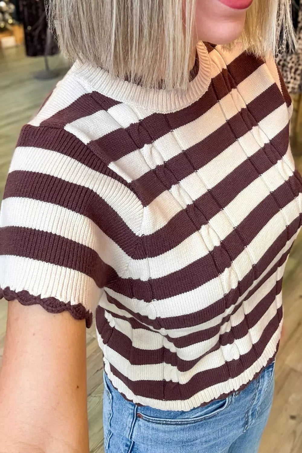 Side close view of brown and cream striped knit sweater showing scalloped short sleeve edge.