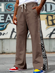 Men's dark brown wide-leg pants with side snaps and a drawstring waist.