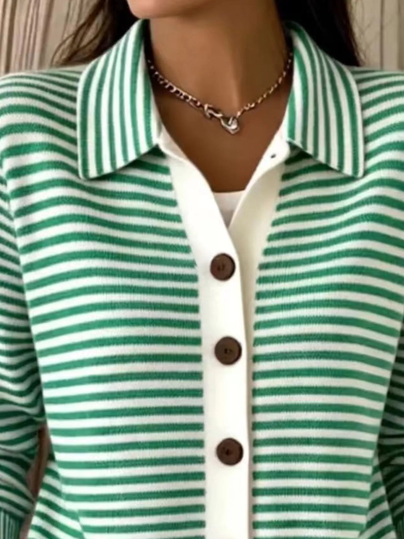 Close-up of the collar and brown buttons on a green and white striped knit cardigan