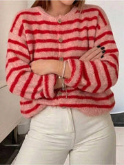 Front view of pink and red striped button down cardigan with arms crossed and white pants